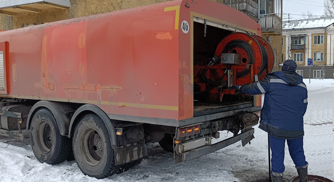 Каналопромывочная машина и работник прочищают засор в канализационной системе в Комсомольске
